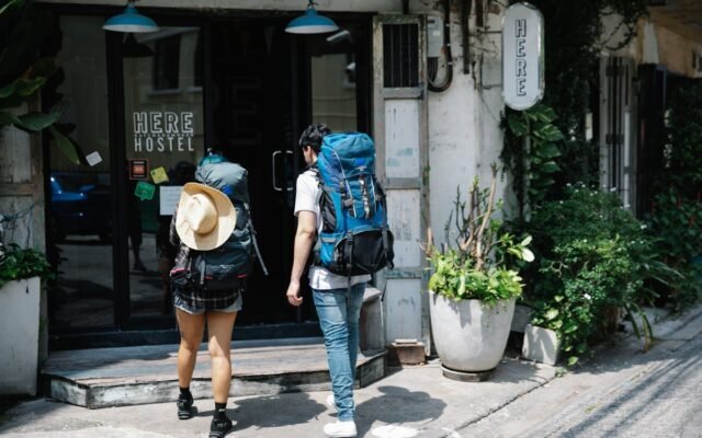 Zwei Rucksacktouristen betreten an einem sonnigen Tag ein Hostel und erkunden das Reisen in der Stadt
