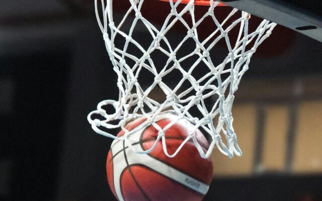 Ein Basketball fliegt mitten in der Aktion durch einen Korb in einer Sporthalle
