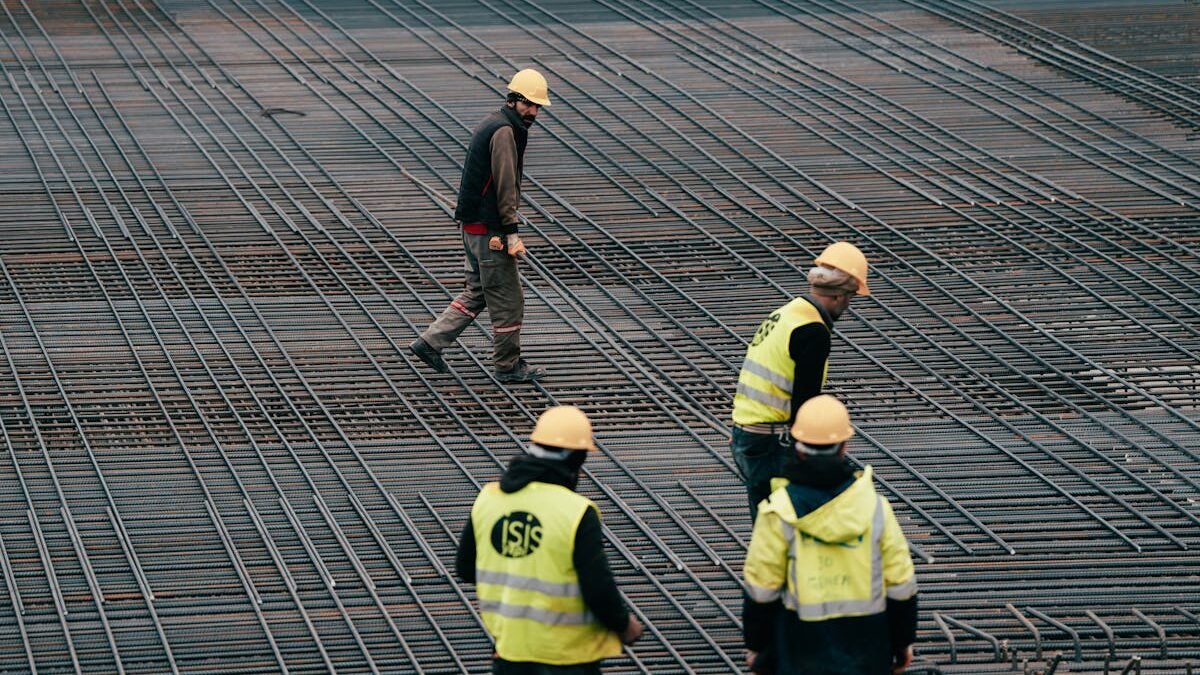 Arbeiter in Schutzkleidung auf einer Baustelle mit Fokus auf Bewehrungsstahl