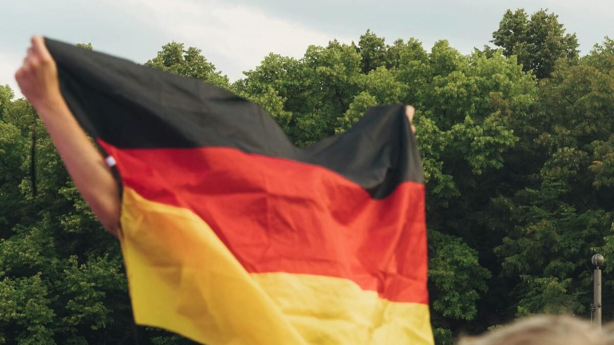 Menschenmenge feiert mit einer Deutschlandfahne bei einer Versammlung im Freien in Berlin