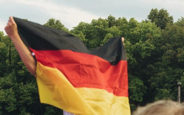 Menschenmenge feiert mit einer Deutschlandfahne bei einer Versammlung im Freien in Berlin