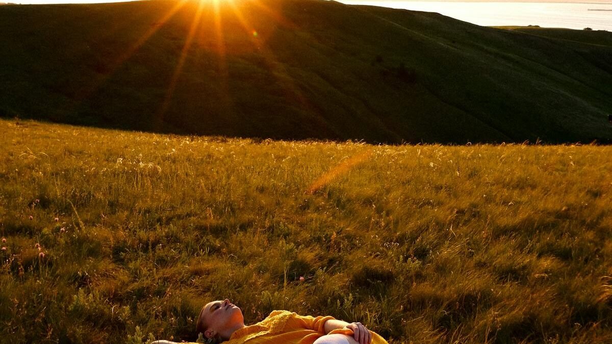 Eine Frau liegt bei Sonnenuntergang auf einem Grasfeld