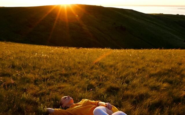 Eine Frau liegt bei Sonnenuntergang auf einem Grasfeld