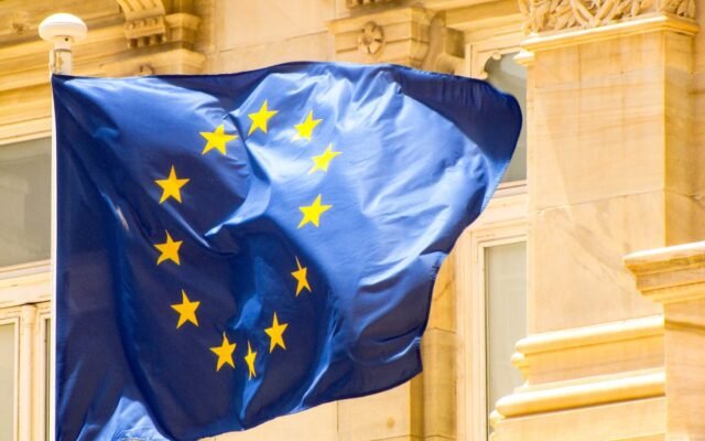 Leuchtende Flagge der Europäischen Union vor historischer Architektur
