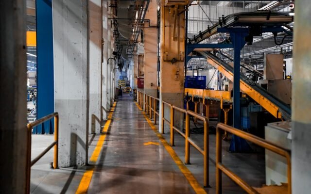 Weite Ansicht eines modernen Fabrikinneren mit Industriemaschinen und Förderbandsystemen