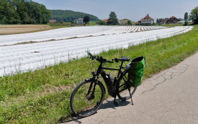 Fahrrad geparkt auf einem ländlichen Pfad neben Schweizer Ackerland unter klarem Himmel