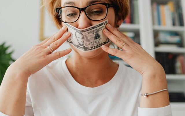 Eine Frau mit Brille nutzt einen Dollarschein als Maske