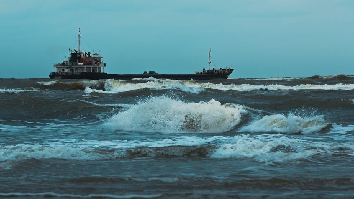 Frachtschiff navigiert durch raue Wellen unter einem bewölkten Himmel. Szene des Seetransports