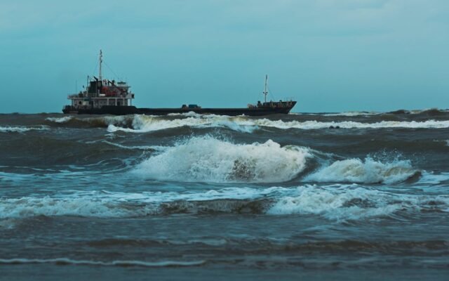 Frachtschiff navigiert durch raue Wellen unter einem bewölkten Himmel. Szene des Seetransports