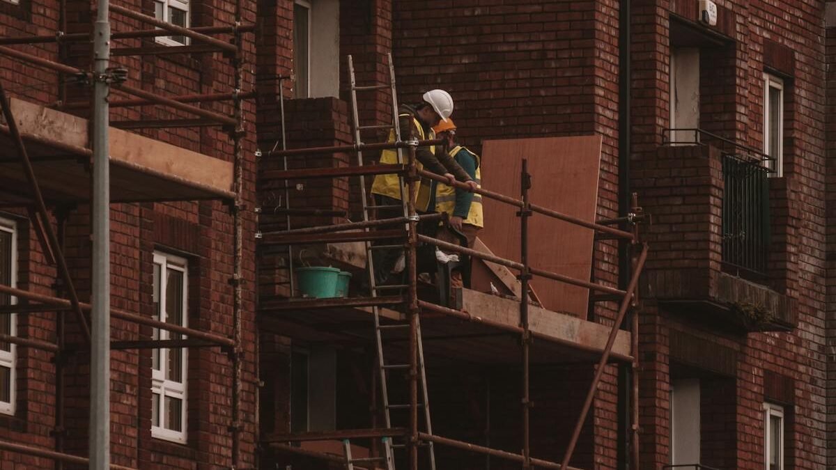 Arbeiter renovieren ein backsteinernes Wohngebäude mit Gerüst im städtischen Raum