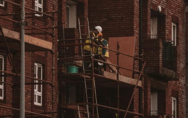 Arbeiter renovieren ein backsteinernes Wohngebäude mit Gerüst im städtischen Raum