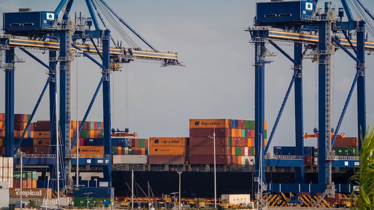 Belebter Industriehafen mit Verladekranen und bunten Schiffscontainern