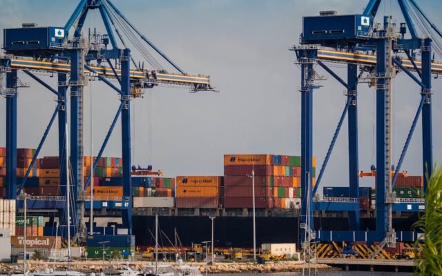 Belebter Industriehafen mit Verladekranen und bunten Schiffscontainern