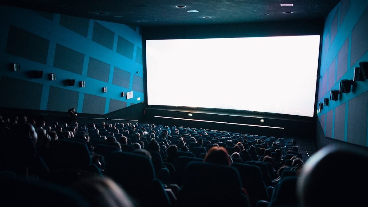 Ein überfülltes Kinopublikum sitzt im Theater und schaut einen Film auf einer großen Leinwand
