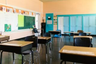 Helles und farbenfrohes leeres Klassenzimmer mit Schreibtischen