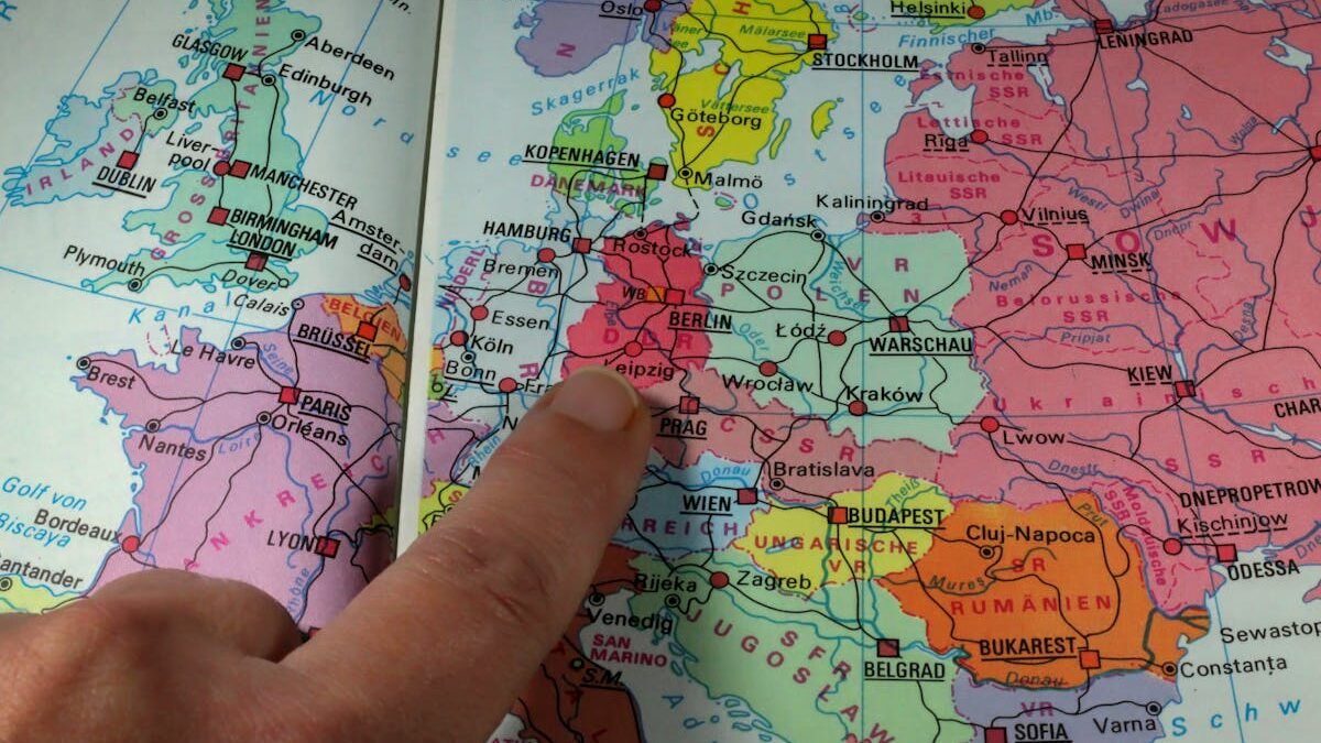 Ein Finger zeigt auf Berlin auf einer farbenfrohen politischen Landkarte von Europa aus der Zeit des Kalten Krieges