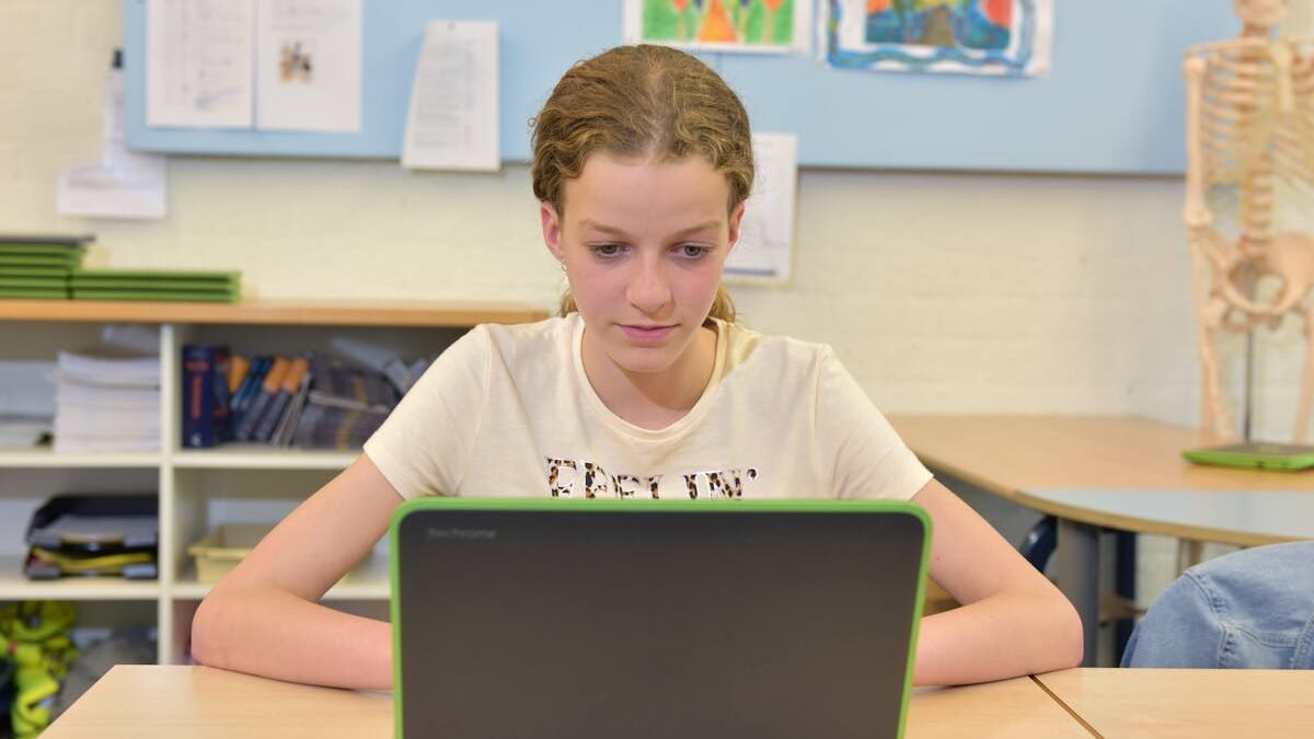 Mädchen kaukasischer Herkunft konzentriert am Laptop in einem Klassenzimmer beim Lernen