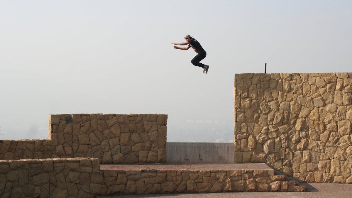 Ein Athlet vollführt einen spannenden Parkour-Sprung zwischen Steinmauern