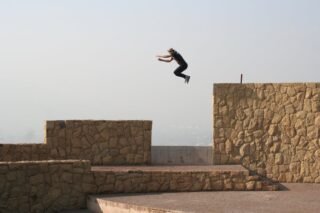 Ein Athlet vollführt einen spannenden Parkour-Sprung zwischen Steinmauern