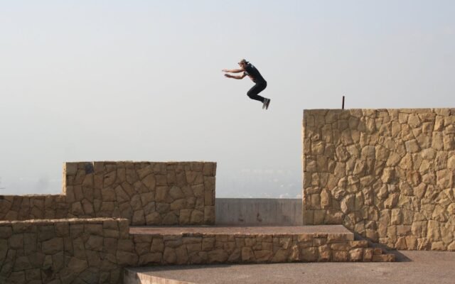 Ein Athlet vollführt einen spannenden Parkour-Sprung zwischen Steinmauern