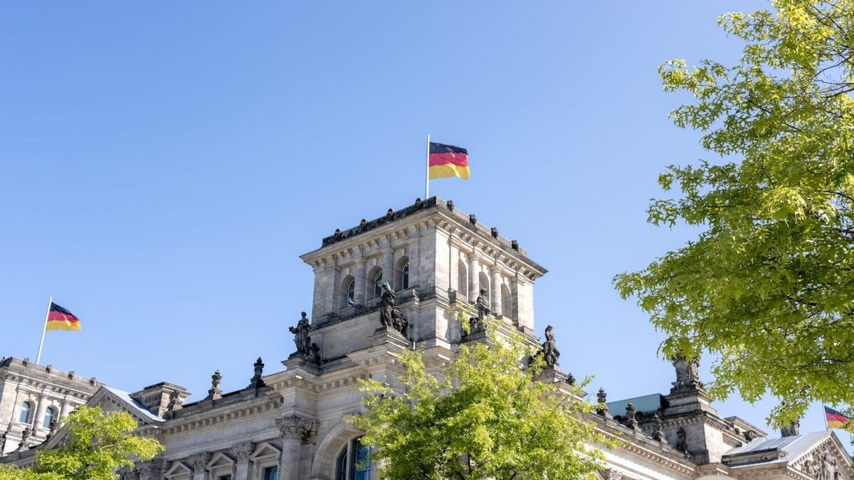 Reichstagsgebäude in Berlin mit deutschen Flaggen an einem sonnigen Tag