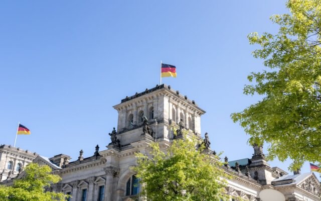 Reichstagsgebäude in Berlin mit deutschen Flaggen an einem sonnigen Tag