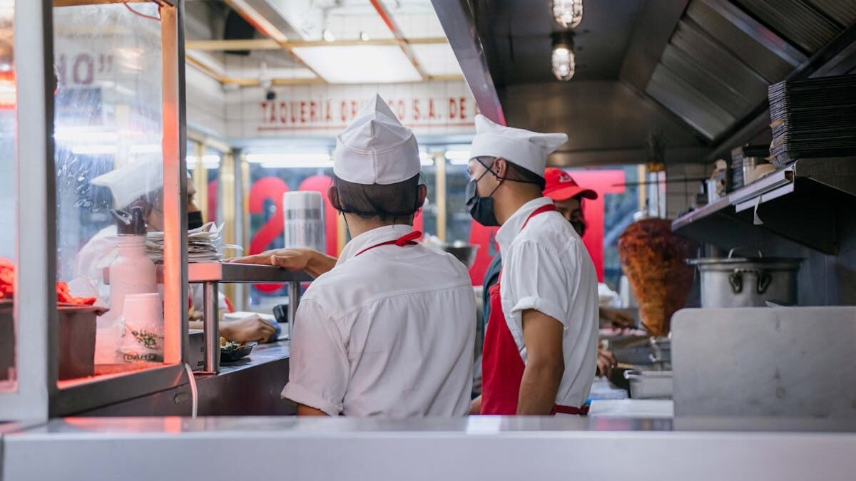 Köche in Uniformen arbeiten in einer offenen Restaurantküche und bereiten Essensbestellungen zu