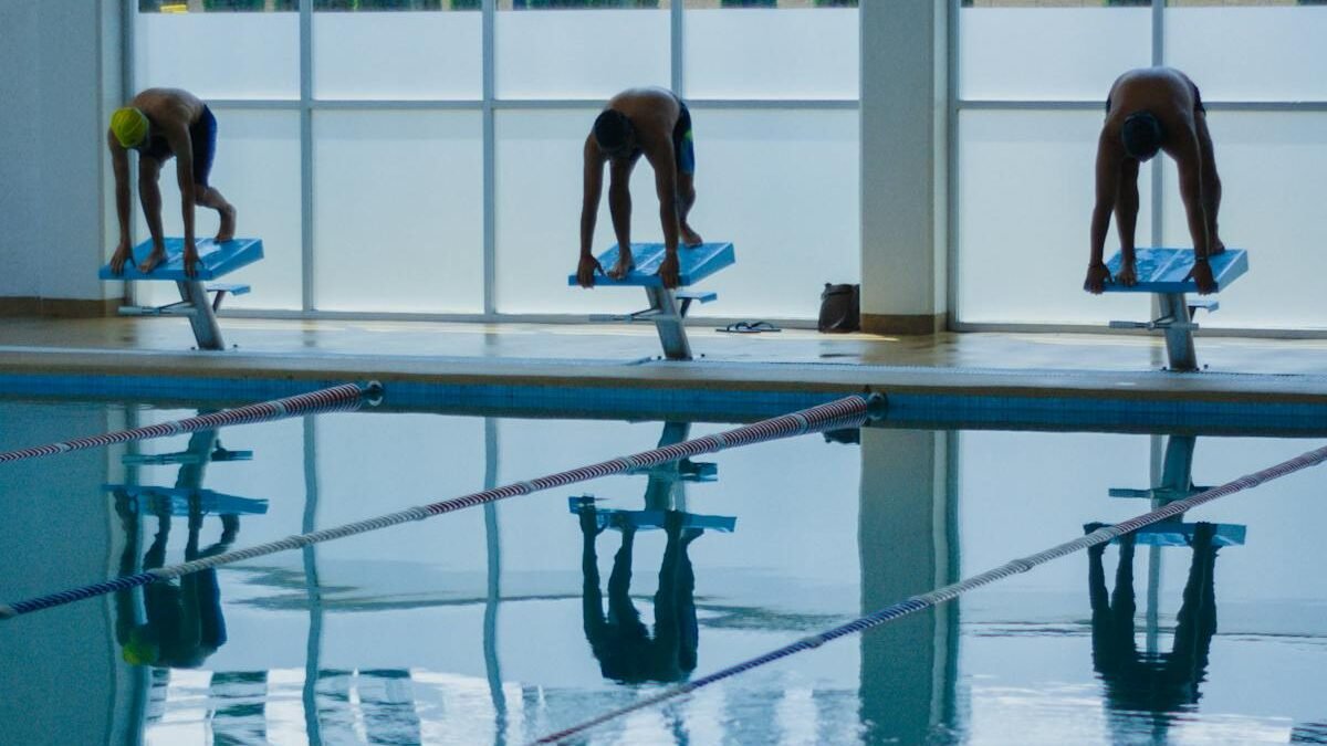 Drei Schwimmer bereit zum Sprung in ein Hallenbad