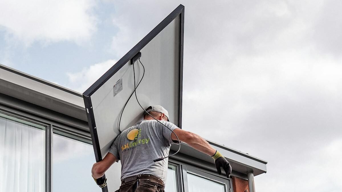 Ein Arbeiter installiert ein Solarpanel auf einem Wohndach und betont erneuerbare Energien