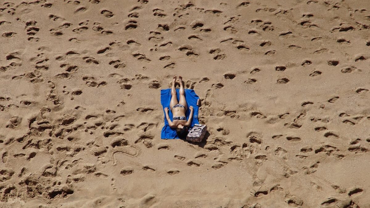 Eine Frau im Bikini sonnt sich an einem Sandstrand