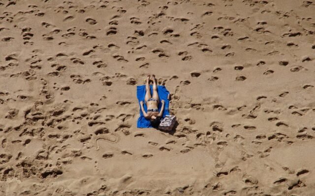 Eine Frau im Bikini sonnt sich an einem Sandstrand