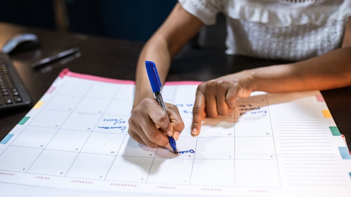 Eine Frau markiert wichtige Termine auf ihrem Schreibtischkalender und plant kommende Ereignisse