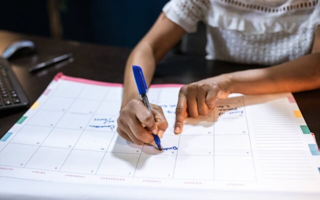 Eine Frau markiert wichtige Termine auf ihrem Schreibtischkalender und plant kommende Ereignisse