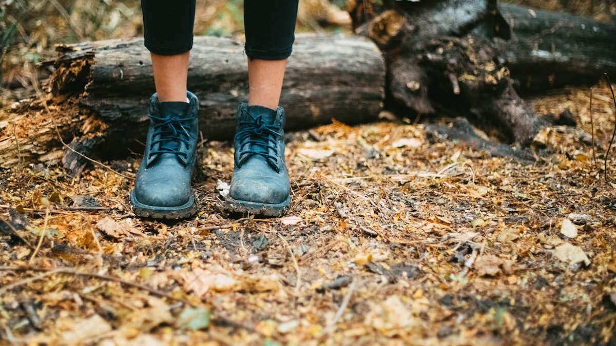 Schwarze Lederstiefel stehen auf einem Waldboden