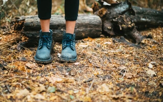 Schwarze Lederstiefel stehen auf einem Waldboden